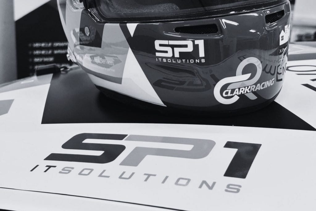 Close-up of Simon Clark’s racing helmet and SP1 IT Solutions branding on a Porsche 911 at the 2025 Porsche Club Championship